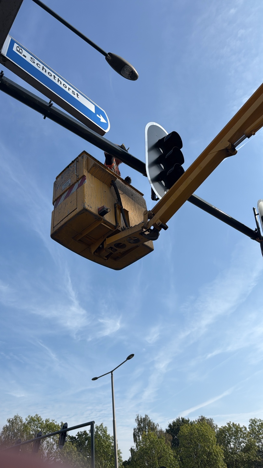 Schilderwerk aan een verkeersregelinstallatie vanuit een hoogwerker