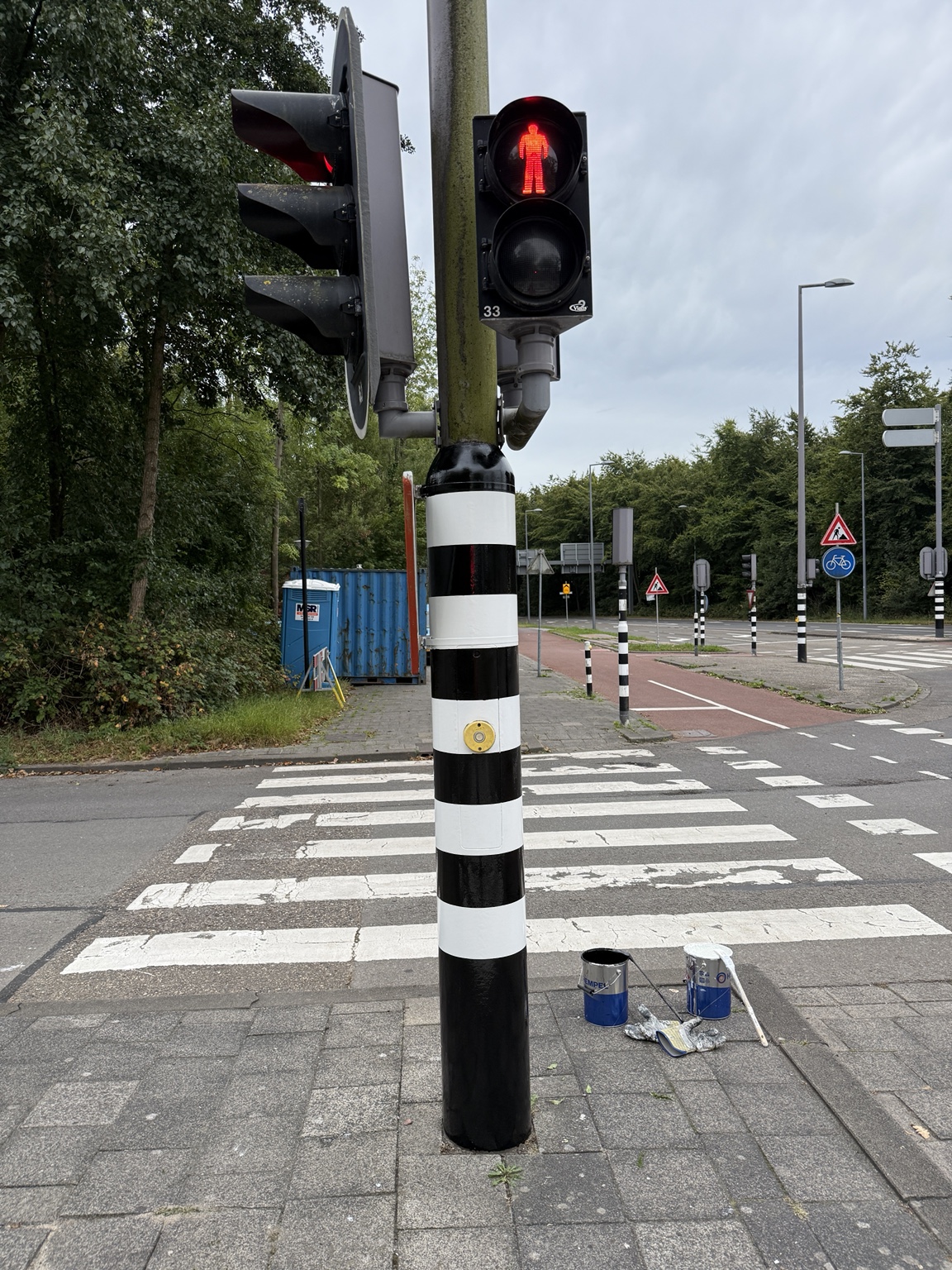 Dezelfde verkeerslichtmast na het schilderen van de zwart-witte banden